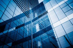 Glass exterior of a modern office building reflecting the sky, representing commercial HVAC maintenance services.